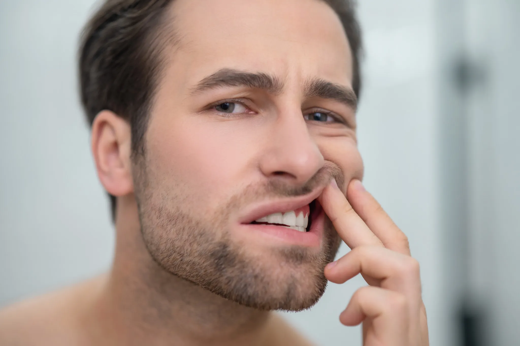 Man checking swollen gums in mirror, showing early signs of gum disease needing treatment in Fairfield dental clinic