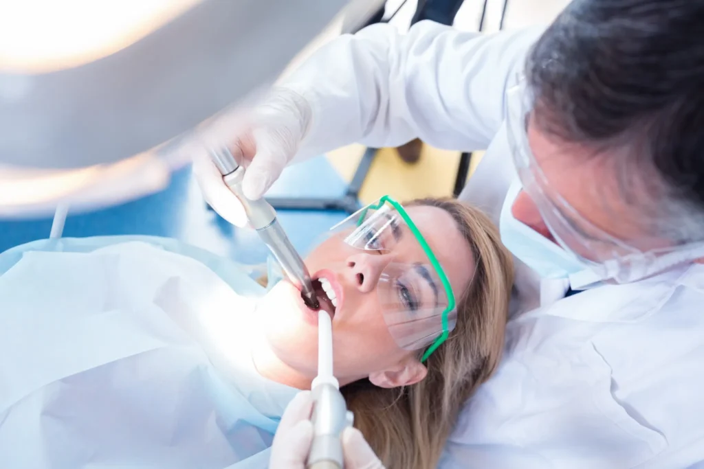 Close-up of a dentist cleaning a patient's teeth using suction and polishing tools during a dental visit in Fairfield