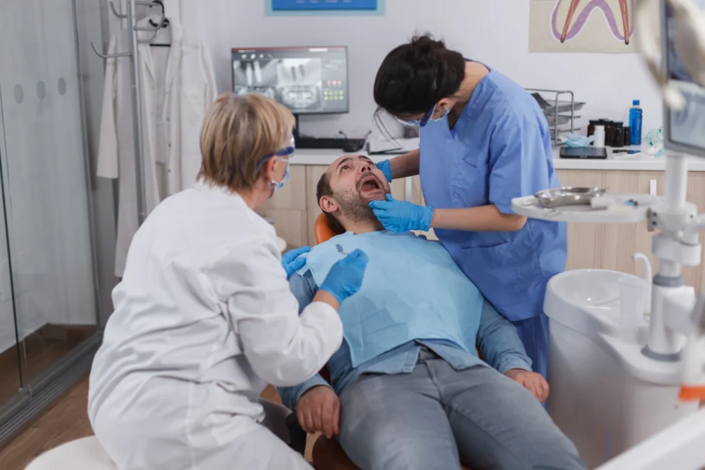 Dentist and assistant examining patient during emergency dental treatment in Fairfield clinic