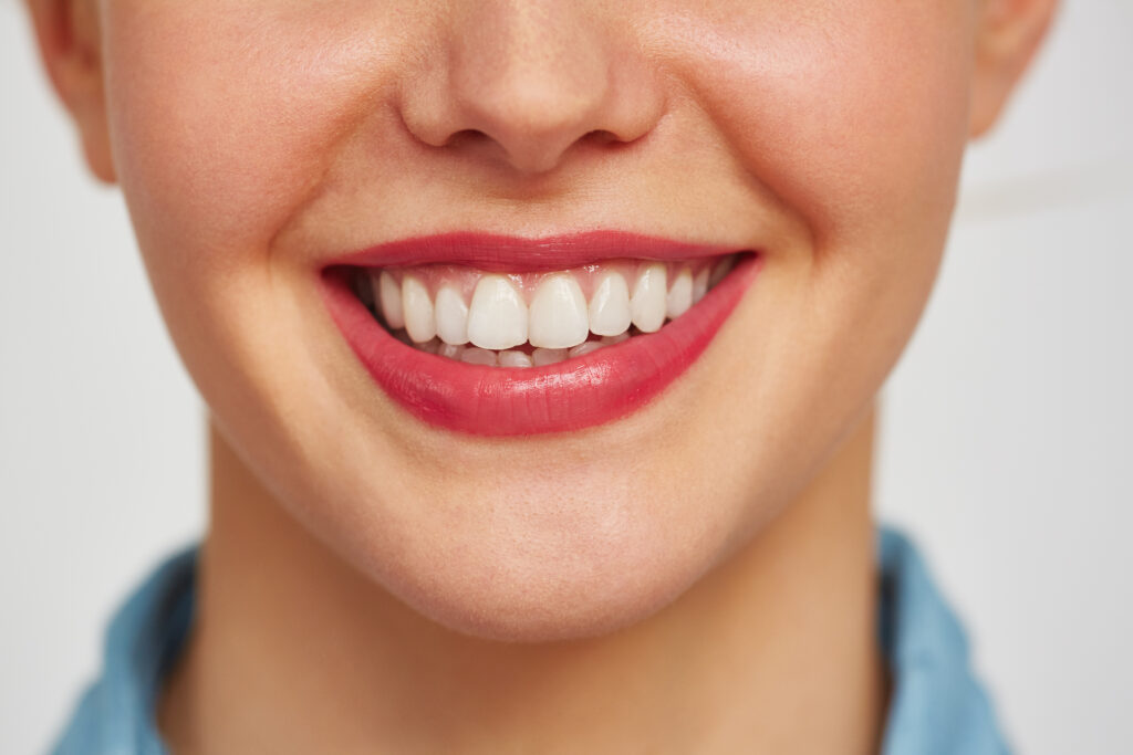 Close-up shot of female face with charming toothy smile against white background